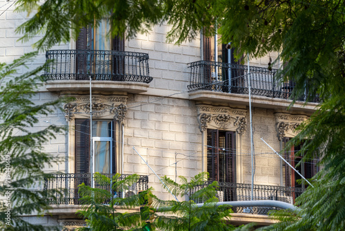 Photography Traditional Barcelona style balconies and green wooden shuttered windows on facade of the renovated house on a sunny day, in the old city of the center