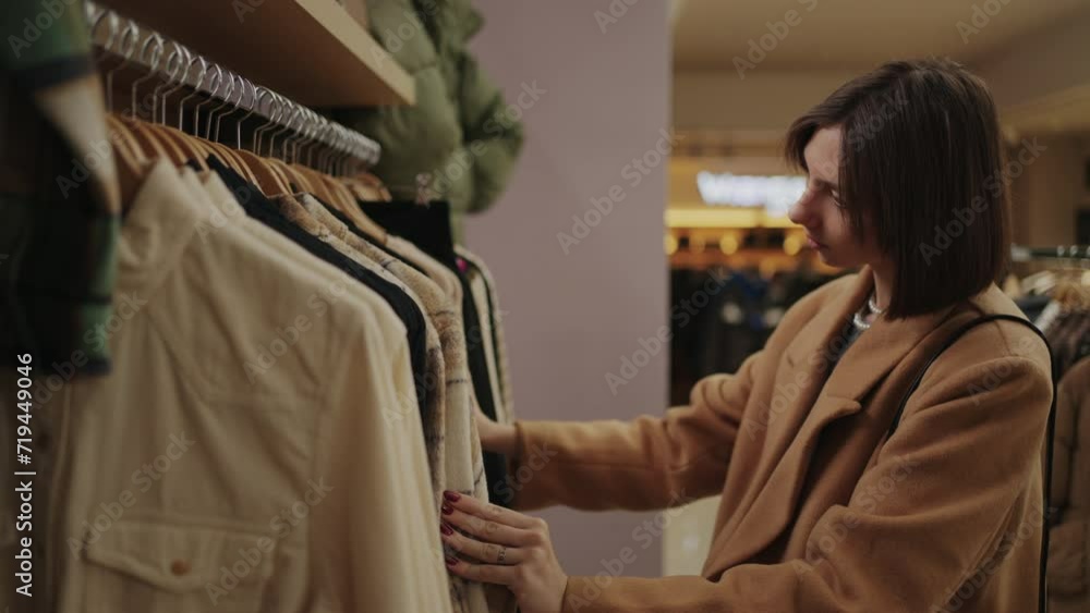 Young Caucasian Woman In Trendy Clothing Store, Lady Viewing And Choosing Gowns Young Caucasian Woman In Trendy Clothing Store, Lady Viewing And Choosing Gowns