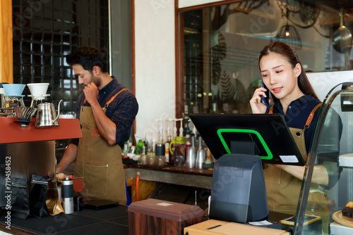 Young barista Businessman, cafe owner, Asian woman and men of different ethnicities. Making coffee orders customers order through ordering machine. young woman taking orders over phone from customers
