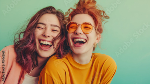 Funny best friends laughing cheerfully while standing together in a studio isolated on pastel green background photo
