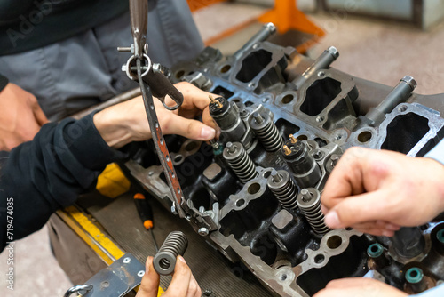 Auto mechanics assembling a disassembled car engine in a workshop