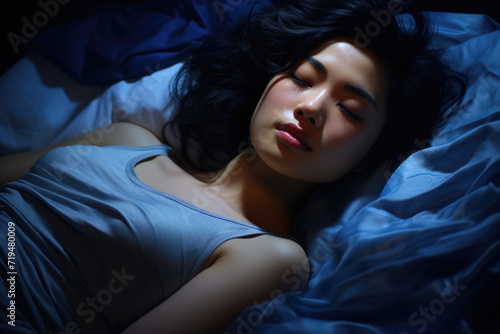 Woman laying in bed with her eyes closed. Can be used to depict relaxation  sleep  or peace