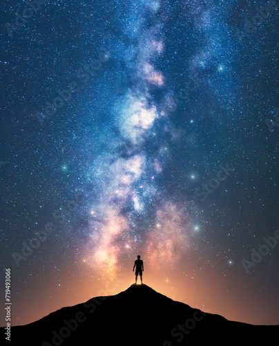 Milky Way and sporty man on mountain peak at starry night