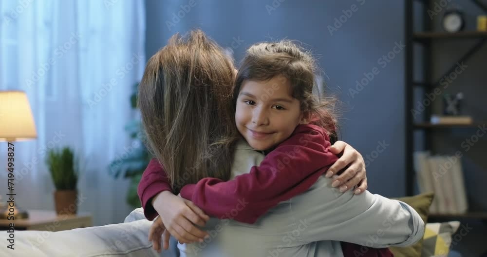 Portrait of a little girl hugging her mother and looking into the camera. Mother's Day concept Portrait of a little girl hugging her mother and looking into the camera. Mother's Day concept