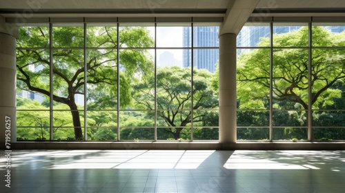 through floor-to-ceiling windows  showcasing the lush green grass and dense woods of a city park beyond.