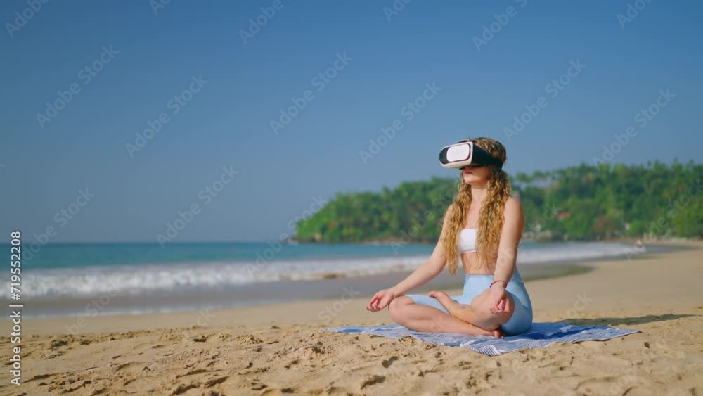 Woman in yoga pose meditates with VR glasses on sandy beach. Virtual retreat experience, practices mindfulness beside sea. Tech meets zen, wellness in nature. Slow motion. Woman in yoga pose meditates with VR glasses on sandy beach. Virtual retreat experience, practices mindfulness beside sea. Tech meets zen, wellness in nature. Slow motion.