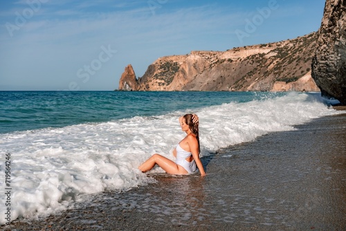 Happy woman in bikini sits on the sea beach. Tanned girl sunbathing on a beautiful shore. Summer vacation or holiday travel concept © svetograph