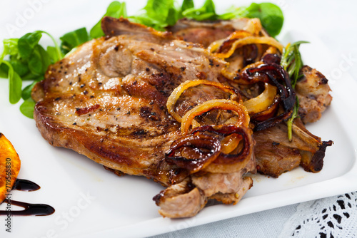 Grilled pork steak served with green salad and grilled orange