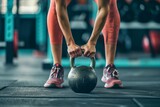 A powerful image capturing a determined woman deadlifting a kettlebell from the ground at the gym, showcasing strength, fitness, and weightlifting prowess