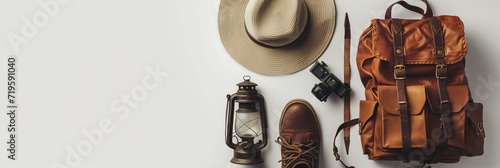 Vintage adventurer essential gear flat lay. Hat, backpack, film camera, gas lamp and boots on white background isolated. Minimal style hiking concept. Wanderlust vibes. photo