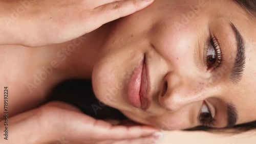 Macro verticap closeup portrait of a woman touching her face tenderly, capturing skincare, wellness, and self-care rituals with a serene expression.