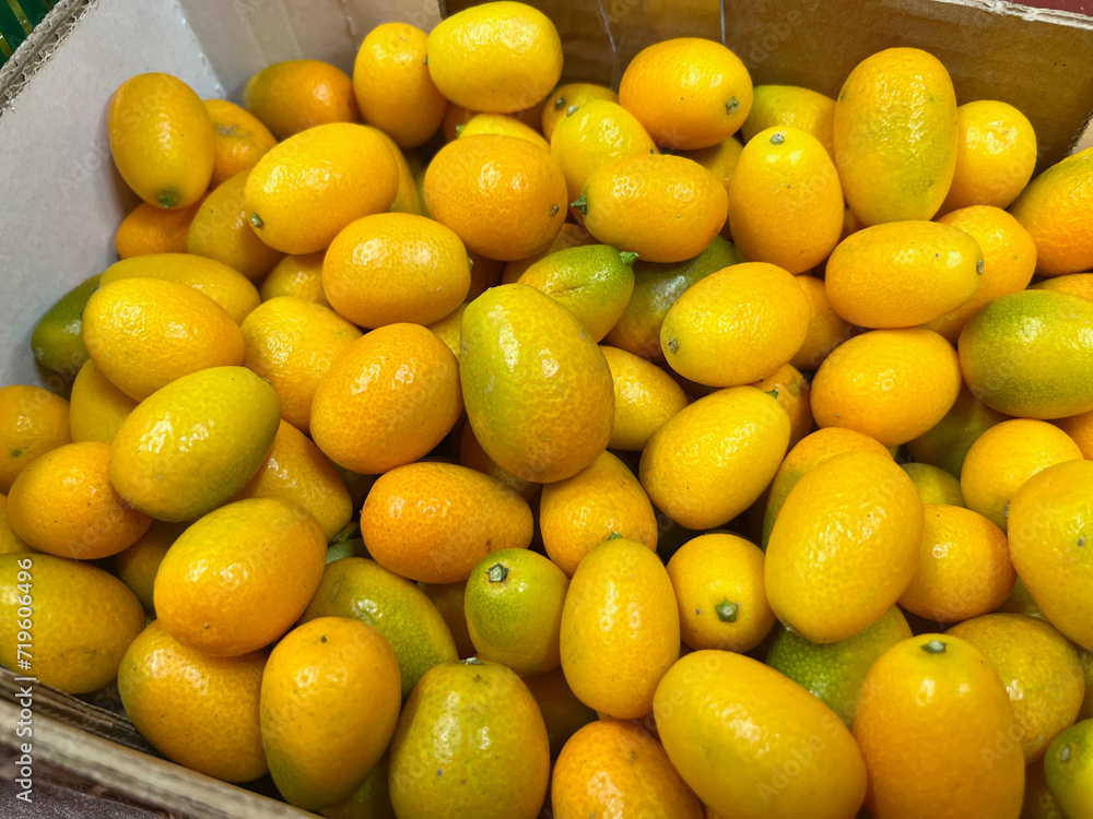 Kumquat in a box at the supermarket. Slightly green fruit. A large amount of vitamins
