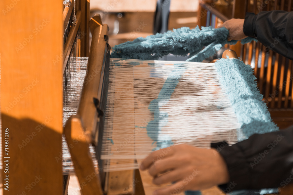Master weaver is weaving the tapestry with diverse bright threads, close up. Artisanal at work