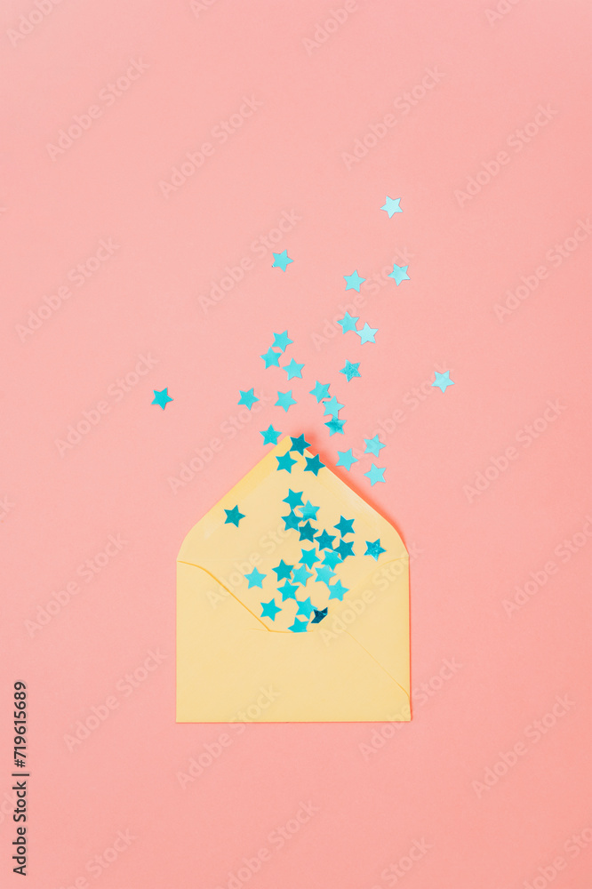 Yellow envelope with blue confetti on pink background. Holiday concept. Top view, flat lay Yellow envelope with blue confetti on pink background. Holiday concept. Top view, flat lay