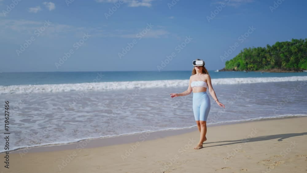 Woman explores virtual world, wearing VR headset on sunny beach, experiences immersive tropical environment, interacts with digital elements unseen to viewer, conveys modern leisure activity. Slowmo Woman explores virtual world, wearing VR headset on sunny beach, experiences immersive tropical environment, interacts with digital elements unseen to viewer, conveys modern leisure activity. Slowmo