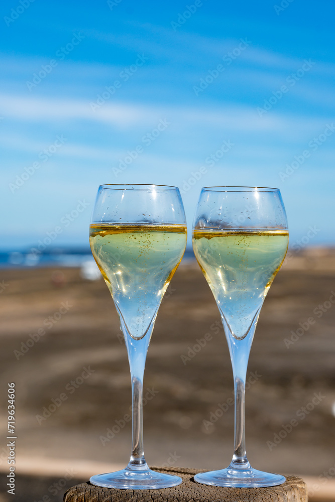 Pouring a glass of champagne on vacation, south of Fuerteventura, Canary islands, blue ocean, mountains