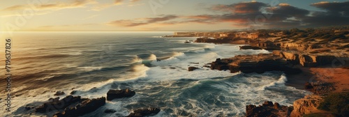 A stunning seascape of crashing waves against the rugged coast, under a vibrant sky as the sun sets on the horizon