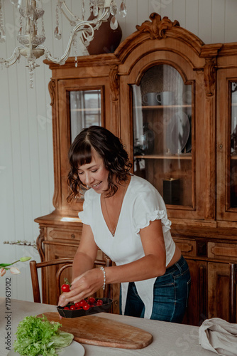 Beautiful girl with dark hair in the kitchen cooking food photo