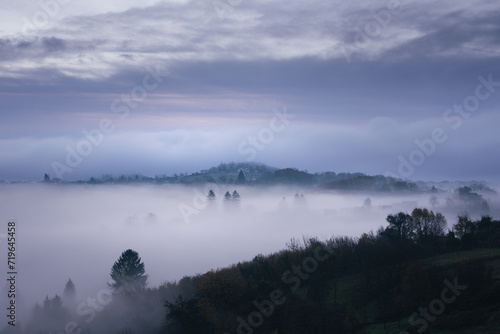 picturesque hilltops peaking out of the fog on the cold frosty autumn morning © Jasenko