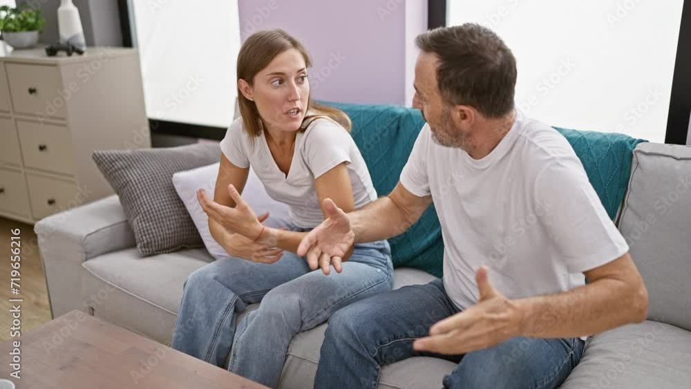 Unhappy father and daughter locked in a heated argument while sitting on the sofa at home, their love stretched thin amid this family disagreement