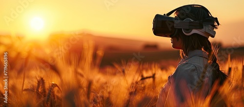 Young man standing in a wheat field at sunset in virtual reality glasses. Copy space image. Place for adding text