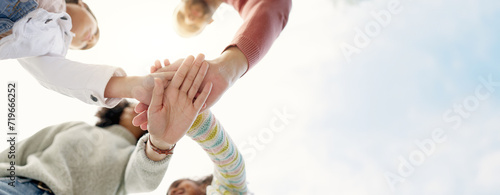 Family, hands together and team in solidarity below for collaboration or celebration under sky. Low angle of mother, father and kids piling for teamwork motivation, support or coordination together photo