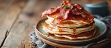 Plate with tasty pancakes and fried bacon on wooden table. Copy space image. Place for adding text