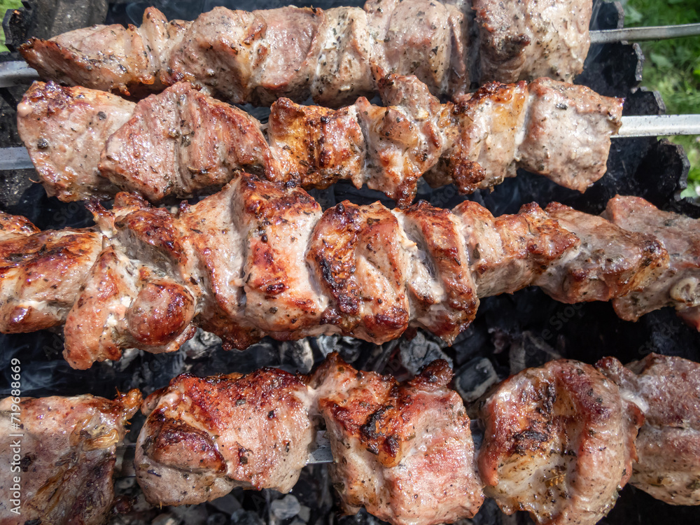 Cooked meat on metal skewers - juicy red meat grilling and cooking on coals on a grill. Herbed and seasoned cubes of meat with brown crust Cooked meat on metal skewers - juicy red meat grilling and cooking on coals on a grill. Herbed and seasoned cubes of meat with brown crust