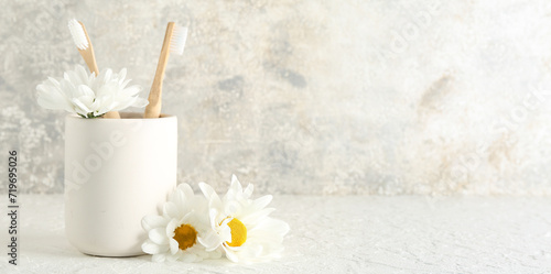 Holder with toothbrushes and chamomile flowers on grunge background. Banner for design