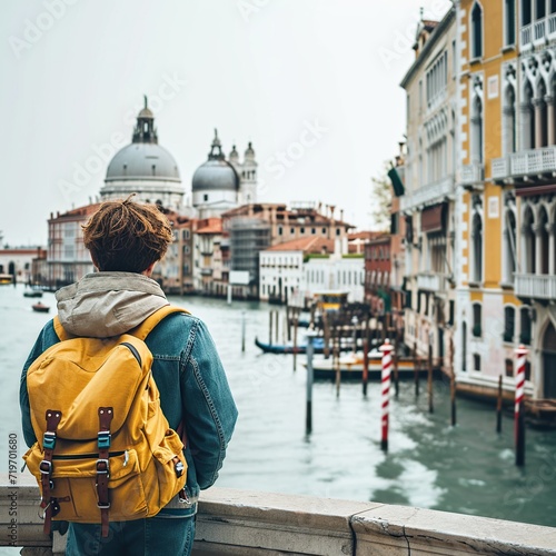 Young man traveling in Venice, Italy. Man with backpack looking at Grand Canal and Basilica Santa Maria della Salute. © Obsidian