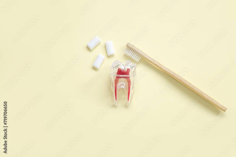 Plastic tooth with brush and chewing gums on light yellow background Plastic tooth with brush and chewing gums on light yellow background