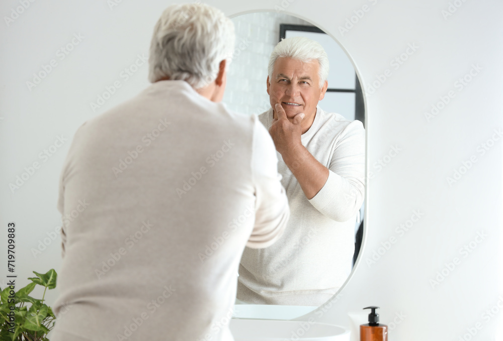 Fototapeta premium Senior man looking in mirror at home