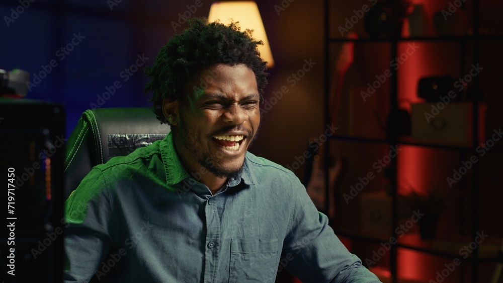 Obraz premium Smiling gamer feeling happy after receiving winner screen on rgb lit PC desktop for killing all enemies. Close up shot of delighted player bragging after being victorious in gaming computer videogame