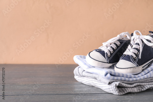Stack of baby clothes and booties on dark wooden table