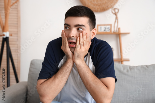 Afraid young man sitting on...