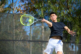 An asian man plays tennis on an outdoor court
