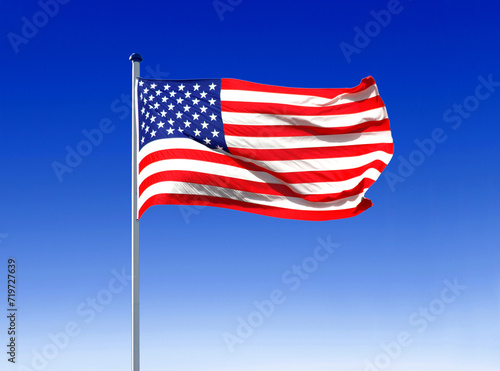 the national flag of the USA flies in the wind on a flagpole with a blue sky as a backdrop