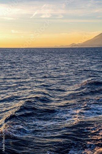 Obraz na płótnie waves on a sea against golden sky and mountain on an island in Greece, Europe w salonie