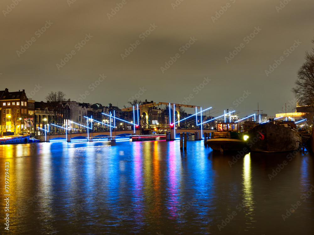 Amsterdam, The Netherlands - December 3, 2022: Illuminated bridge in Amsterdam canal during light festival, Netherlands. High quality photo