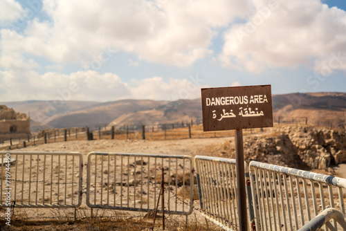 Dangerous area sign with barricades with arabic writing in the middle east. stone path scene with warm tones