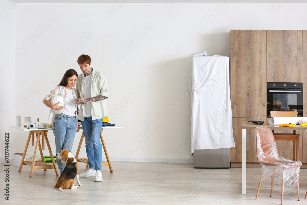 Young couple with Beagle dog using mobile phone during repair in their new house Young couple with Beagle dog using mobile phone during repair in their new house