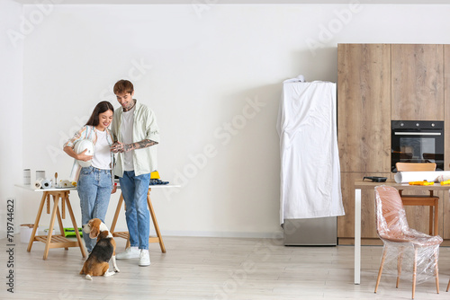 Young couple with Beagle dog using mobile phone during repair in their new house