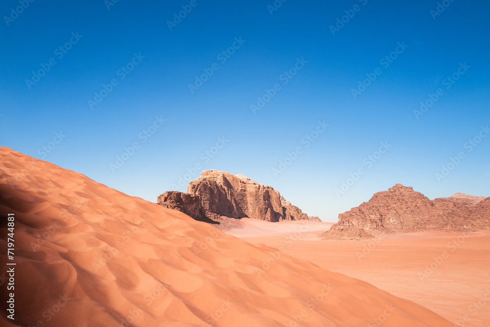 Scenic view of Arabic / Middle Eastern desert against clear blue sky with dune in foreground. Mountain in background and no clouds. Copy space no people