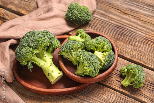 Wooden tray and bowl with fresh green broccoli on wooden background