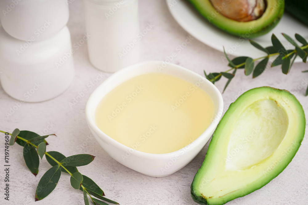 Fresh avocado and bowl with essential oil on white background Fresh avocado and bowl with essential oil on white background