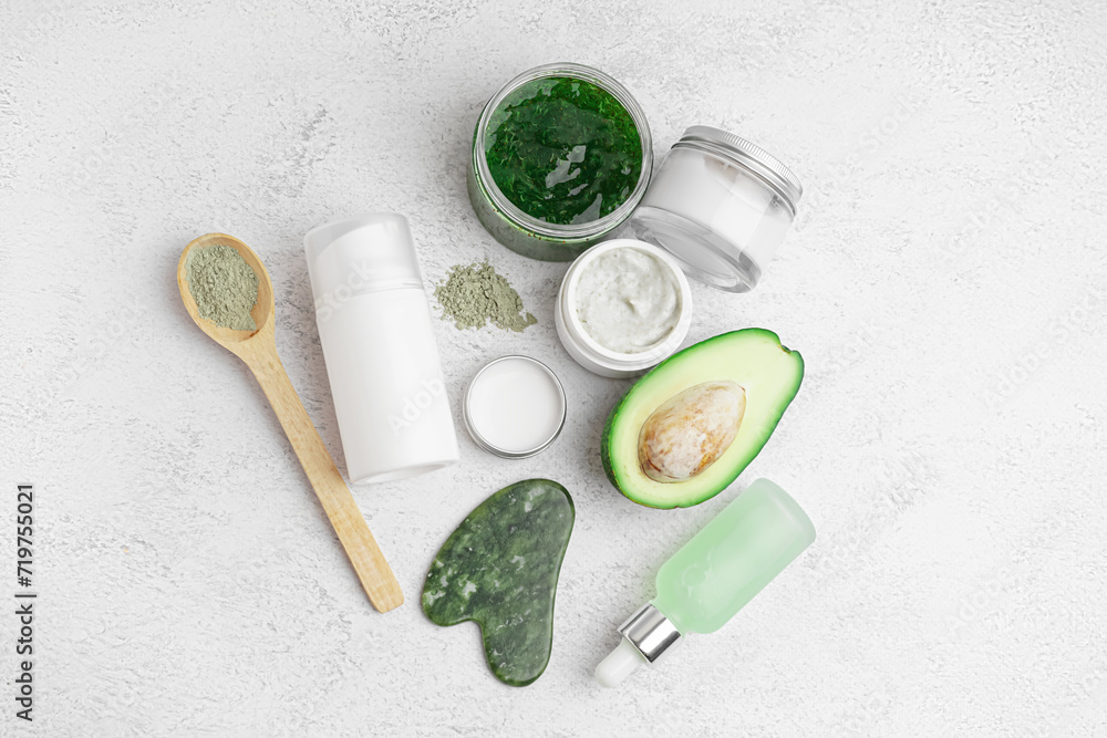 Composition with fresh avocado and jars of cosmetic products on light background Composition with fresh avocado and jars of cosmetic products on light background