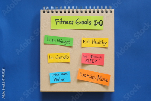 Fitness goals concept. Checklist of goals in note pad in blue background with copy space.