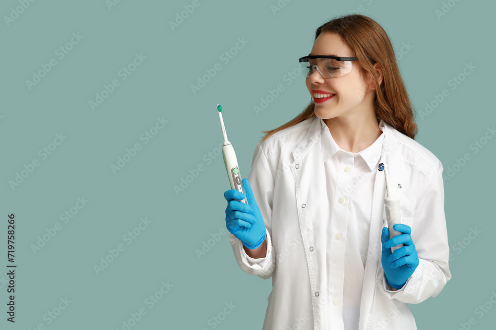 Female dentist with electric toothbrushes on blue background. World Dentist Day Female dentist with electric toothbrushes on blue background. World Dentist Day