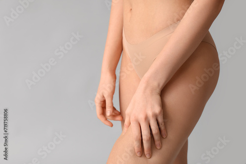 Beautiful young woman with cellulite problem on grey background, back view