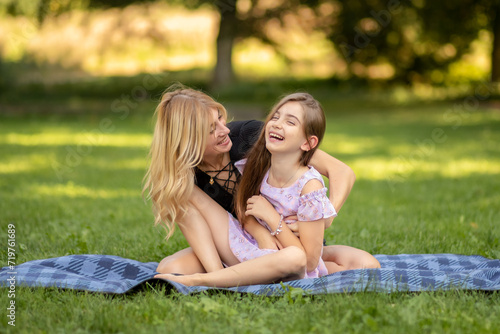 Mother and daughter laughing while sitting on a picnic blanket